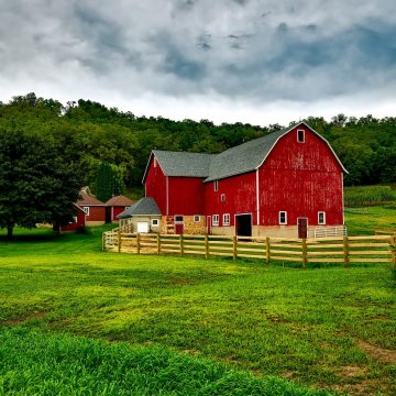 a red barn surrounded by a wooden gate on a farm